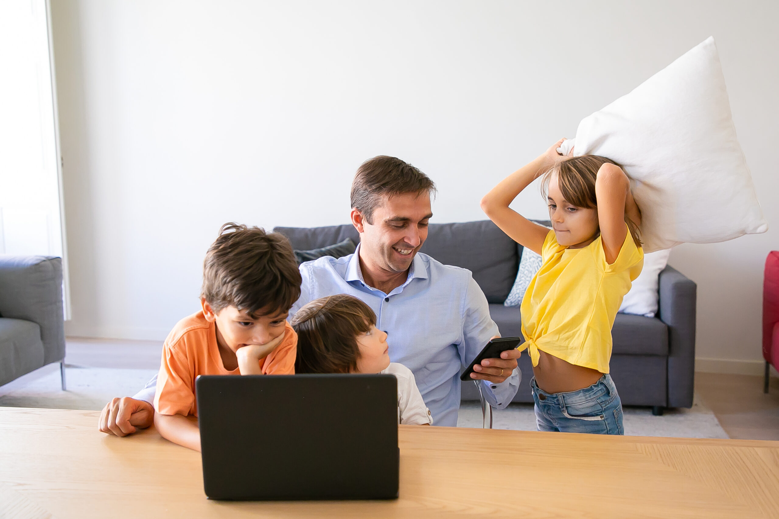 happy-dad-using-smartphone-sitting-table-kids-playing-with-him-caucasian-father-working-home-using-laptop-watching-children-fatherhood-childhood-digital-technology-concept
